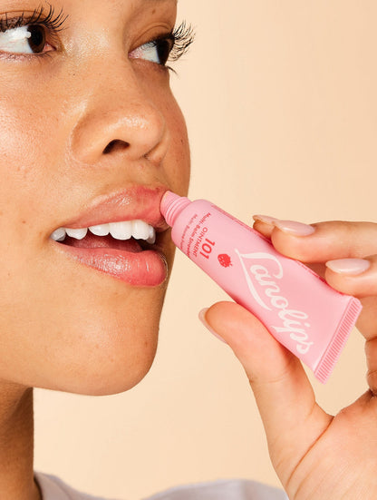 Model applying Lanolips 101 Ointment Multi-Balm in Strawberry to lips, infused with real strawberry extract and vitamin E for sweet, natural hydration. A fruity twist on the iconic Lanolips Original 101 Ointment.