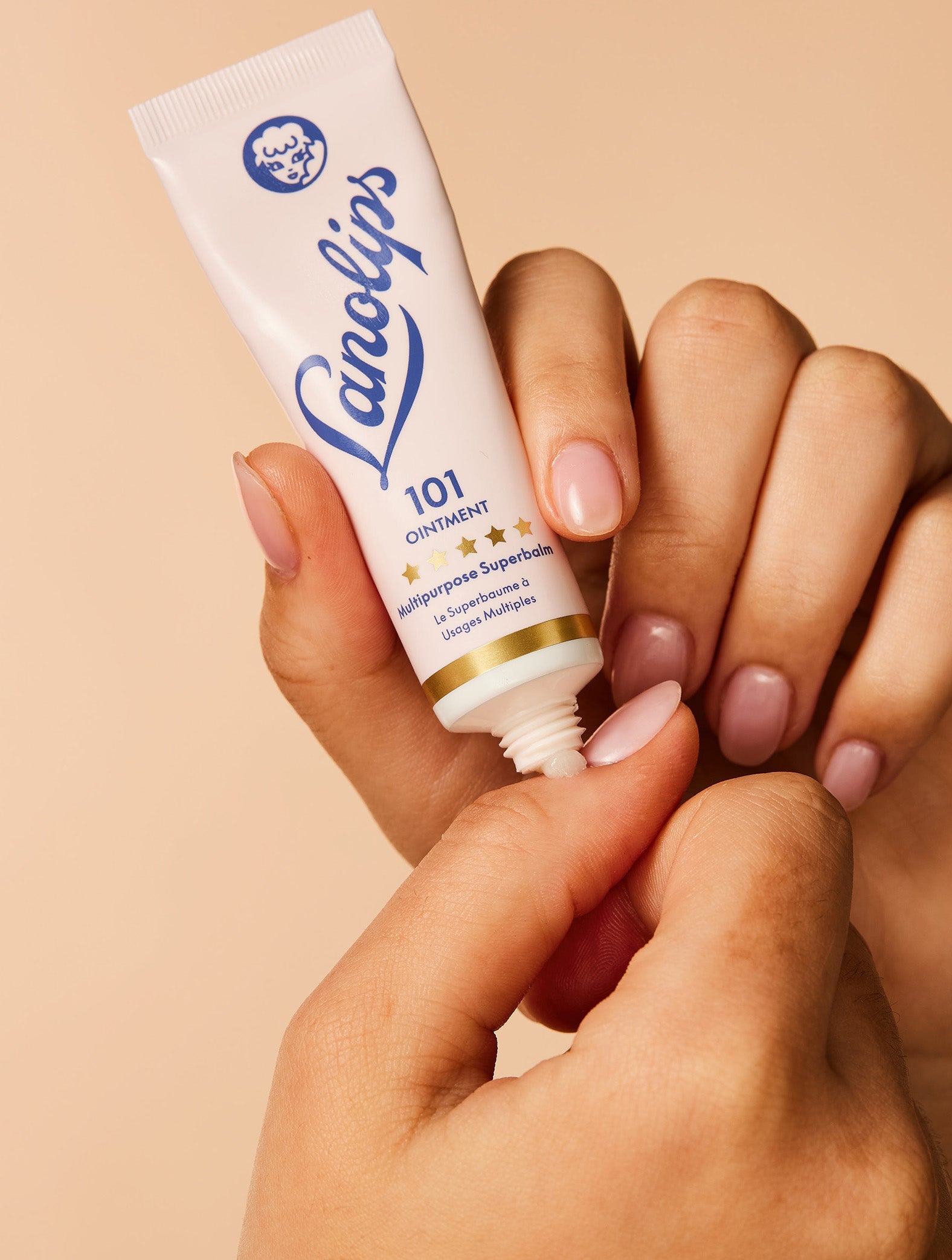 Close up shot of model applying the Lanolips Original 101 Ointment Multipurpose Superbalm on her cuticles. This multipurpose lanolin-based balm provides deep hydration and nourishment for dry skin, lips and cuticles.